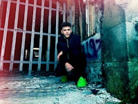 a man crouching in front of a broken down building
